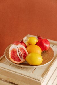 Colorful fruit arrangement with citrus and pomegranates on wooden crate.